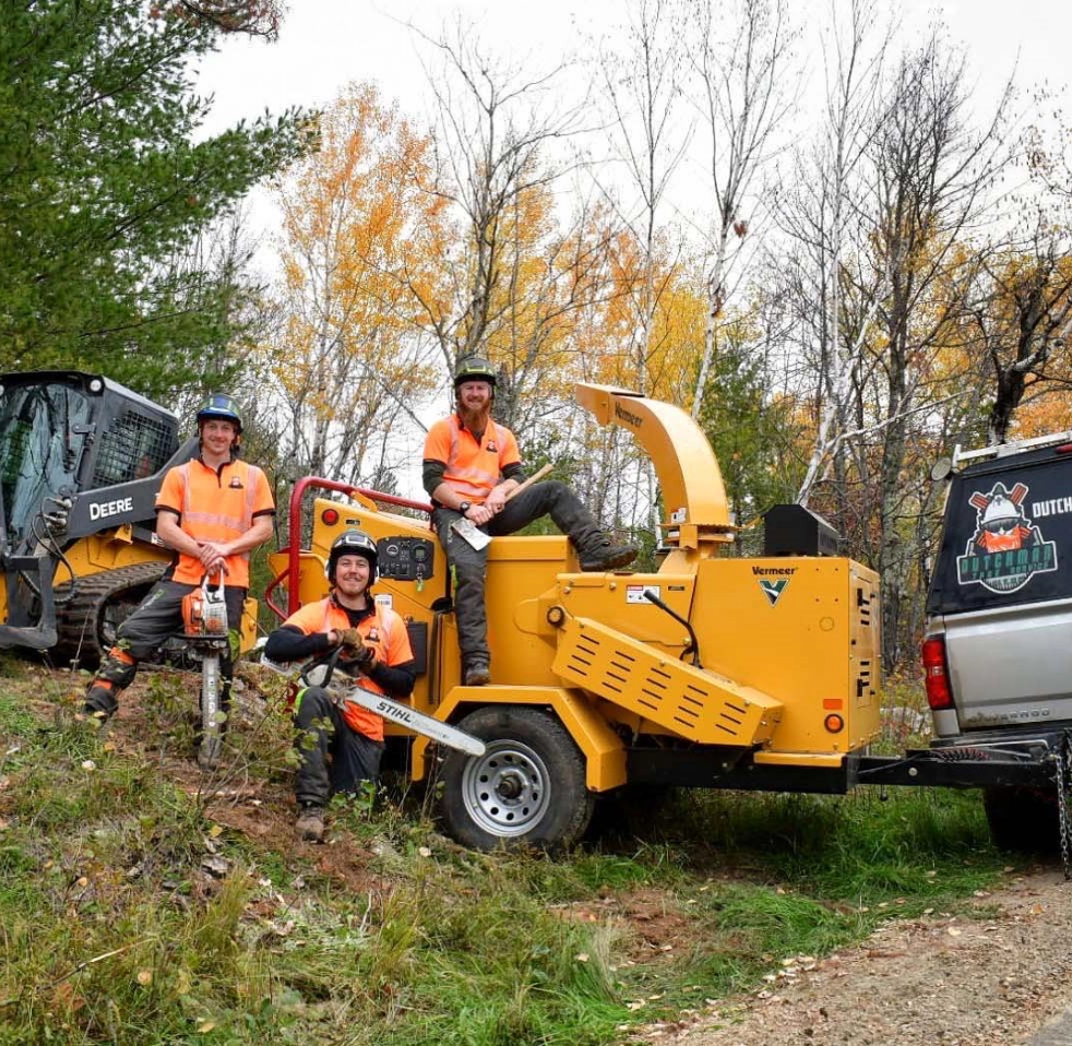 trees in the background of Dutchman Tree Service workers with equipment