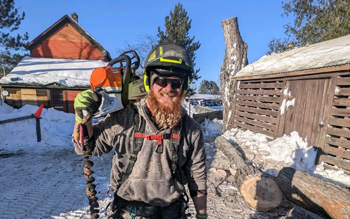 tree service worker carrying a chainsaw